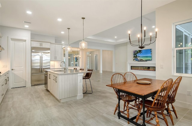 dining space with an inviting chandelier, a tray ceiling, and sink