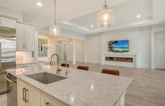 kitchen with a raised ceiling, sink, and hanging light fixtures