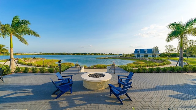 surrounding community featuring a fire pit, a patio area, and a water view