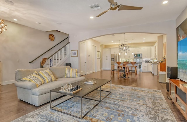 living room featuring hardwood / wood-style flooring and ceiling fan with notable chandelier