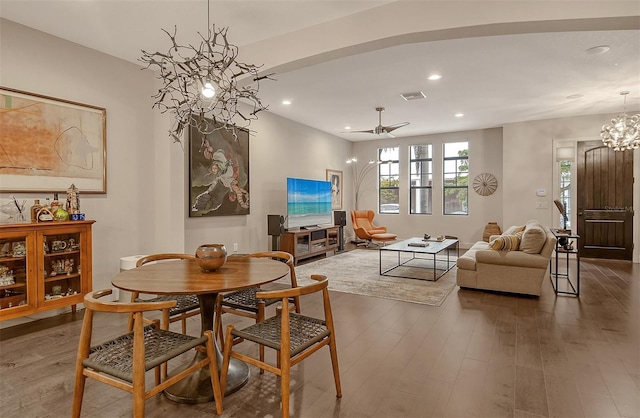 dining area with ceiling fan with notable chandelier and dark hardwood / wood-style flooring