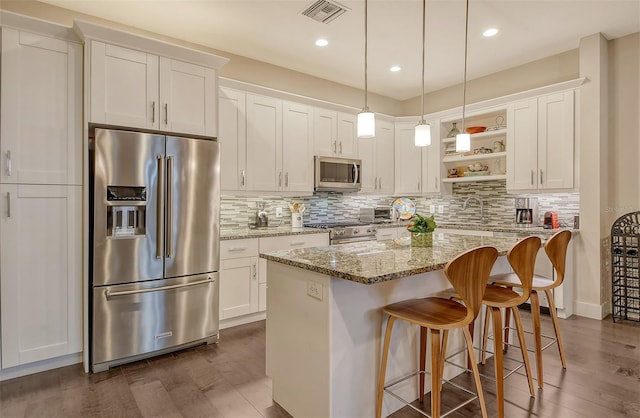 kitchen featuring white cabinets, a kitchen island, light stone countertops, and premium appliances