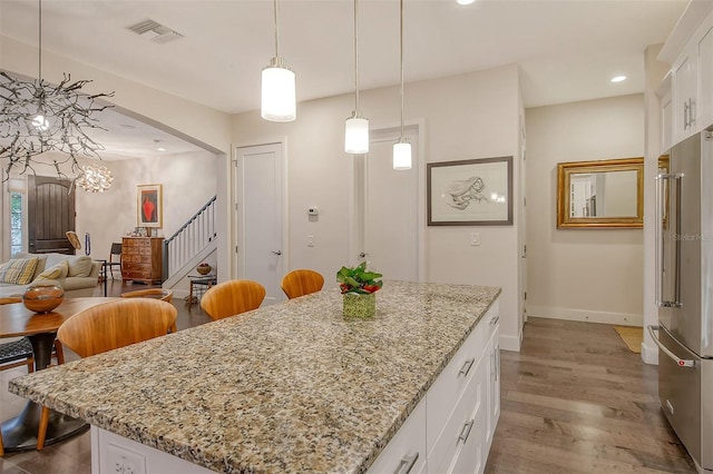 kitchen with white cabinetry, high quality fridge, and hanging light fixtures