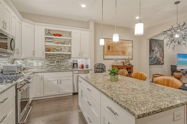 kitchen featuring white cabinets, a kitchen island, appliances with stainless steel finishes, and tasteful backsplash