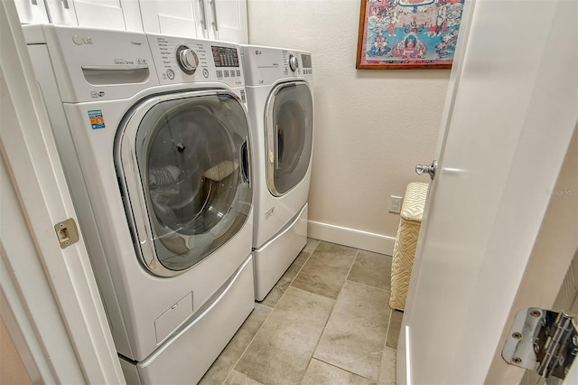 clothes washing area with separate washer and dryer and cabinets