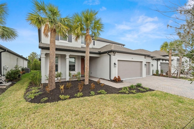 view of front of property with central air condition unit, a front yard, and a garage