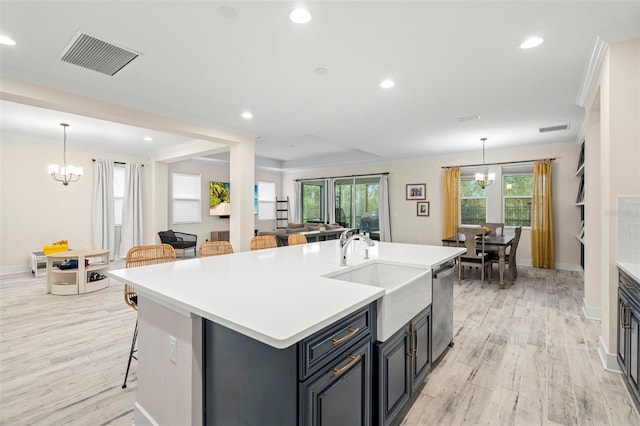 kitchen with decorative light fixtures, a breakfast bar area, dishwasher, and an island with sink