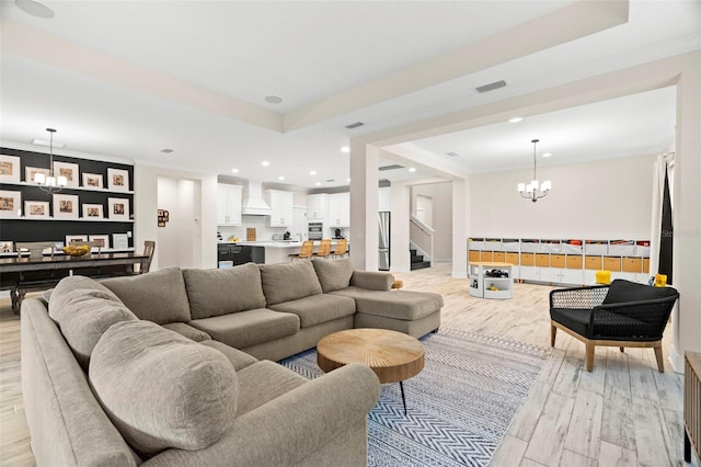 living room with a chandelier, light hardwood / wood-style flooring, and crown molding