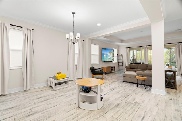 living room featuring crown molding, light wood-type flooring, a tray ceiling, and a notable chandelier