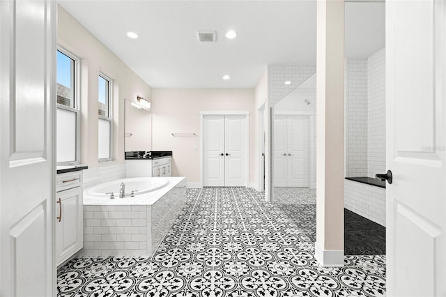 bathroom featuring vanity, tiled tub, and tile patterned floors