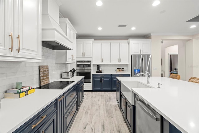 1012 Fernleaf Run, Bradenton, FL 34212 - kitchen featuring stainless steel appliances, premium range hood, blue cabinetry, white cabinets, and light countertops