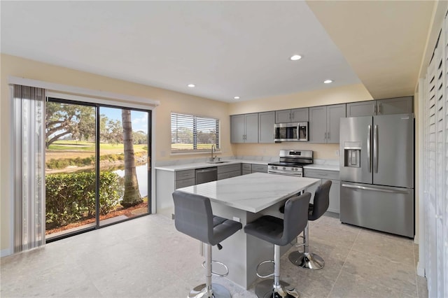 kitchen with sink, a breakfast bar area, light stone counters, a center island, and appliances with stainless steel finishes