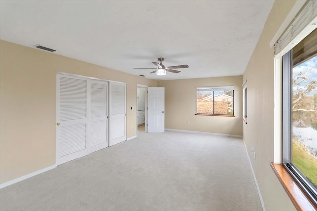 unfurnished bedroom with ceiling fan, a closet, and light carpet