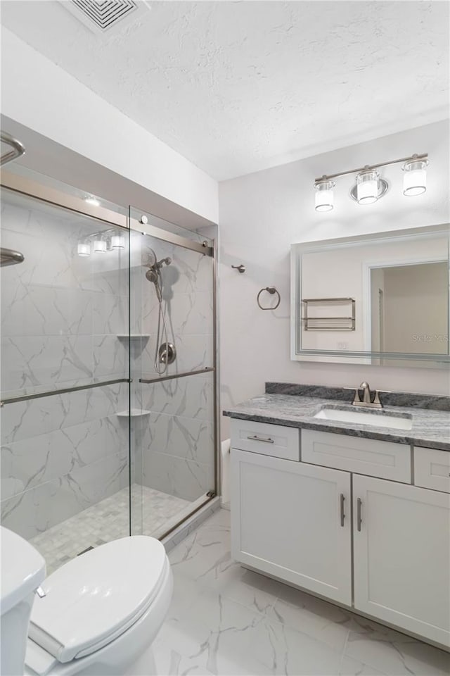 bathroom featuring vanity, a textured ceiling, toilet, and walk in shower