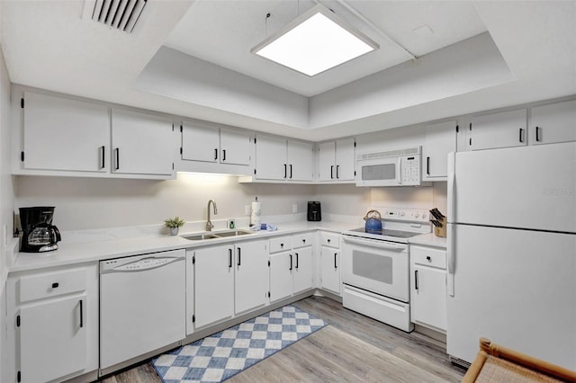 kitchen with white cabinetry, sink, light wood-type flooring, a tray ceiling, and white appliances