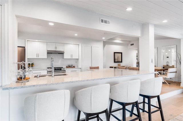 kitchen featuring white cabinetry, sink, light stone counters, and kitchen peninsula