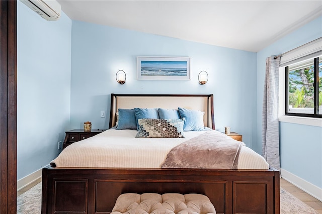 bedroom with a wall mounted air conditioner and light hardwood / wood-style flooring