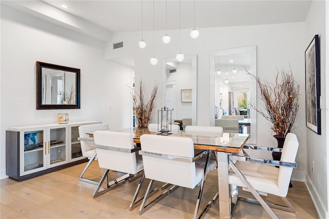 dining room with vaulted ceiling and light wood-type flooring