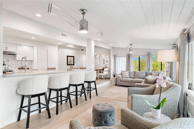 living room featuring wood ceiling, lofted ceiling, sink, and light wood-type flooring