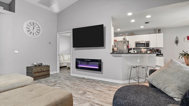 living room with high vaulted ceiling and light hardwood / wood-style floors