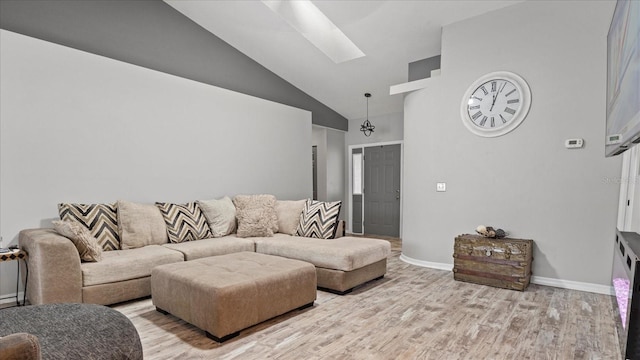 living room with a skylight, high vaulted ceiling, and light hardwood / wood-style flooring