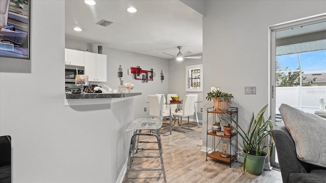 kitchen featuring ceiling fan, white cabinetry, kitchen peninsula, and light hardwood / wood-style floors