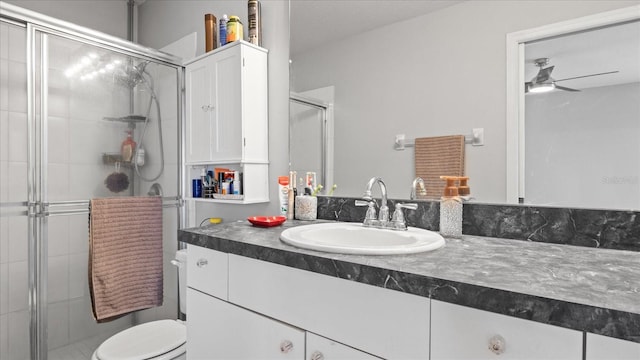 bathroom with vanity, ceiling fan, a shower with shower door, and toilet