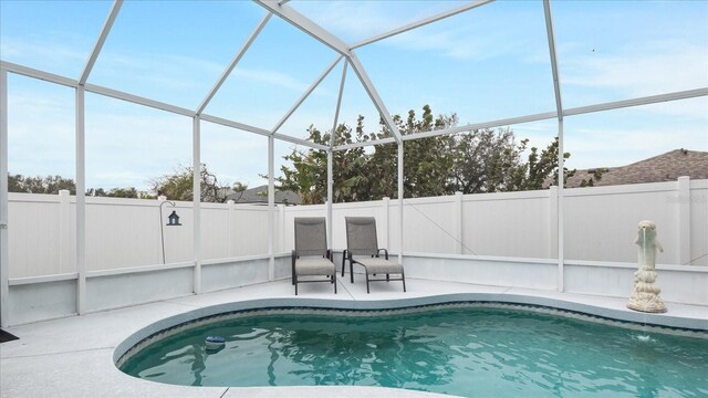 view of swimming pool featuring glass enclosure and a patio