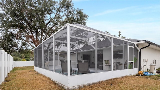 rear view of property with glass enclosure, a patio area, a pool, and a lawn