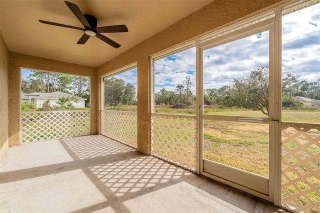 unfurnished sunroom with ceiling fan and plenty of natural light