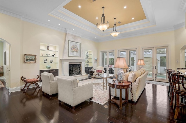 living room featuring a tray ceiling, dark hardwood / wood-style floors, a high end fireplace, and french doors