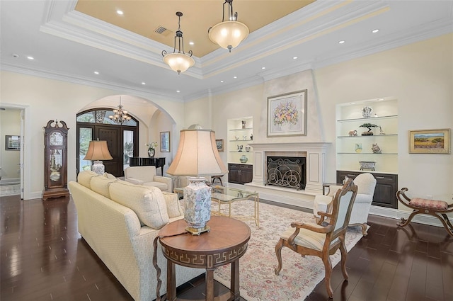 living room featuring crown molding, a tray ceiling, dark hardwood / wood-style flooring, built in features, and a high end fireplace