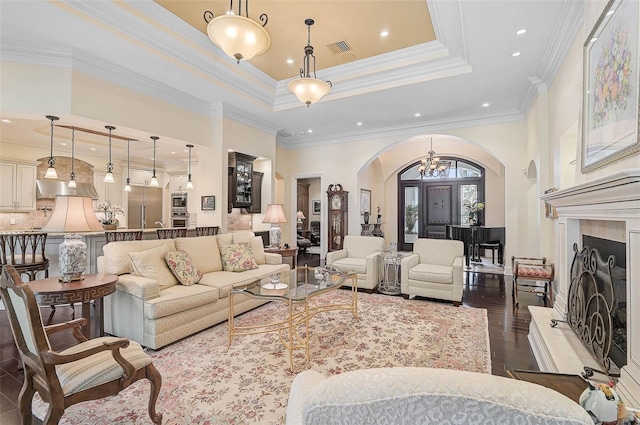 living room with a raised ceiling, ornamental molding, a chandelier, and dark hardwood / wood-style flooring