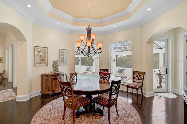 dining room with a raised ceiling, ornamental molding, an inviting chandelier, and dark hardwood / wood-style flooring