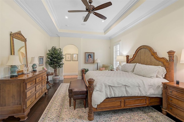 bedroom with crown molding, ceiling fan, a tray ceiling, and dark hardwood / wood-style flooring