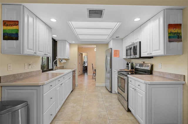 kitchen with sink, light tile patterned flooring, white cabinets, and appliances with stainless steel finishes