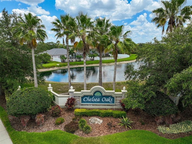 community sign featuring a water view and a lawn