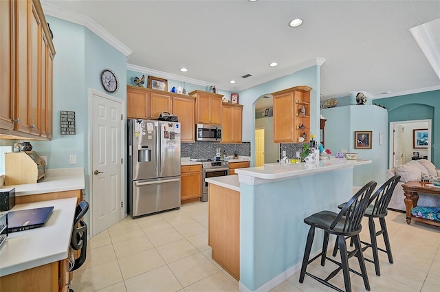 kitchen with crown molding, stainless steel appliances, kitchen peninsula, and a kitchen bar