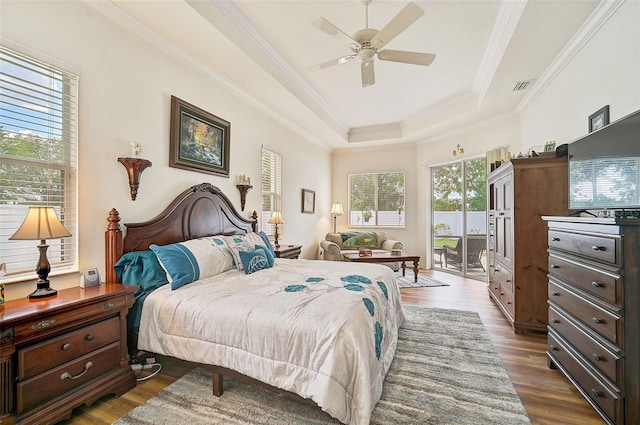 bedroom with access to exterior, crown molding, dark wood-type flooring, and a raised ceiling