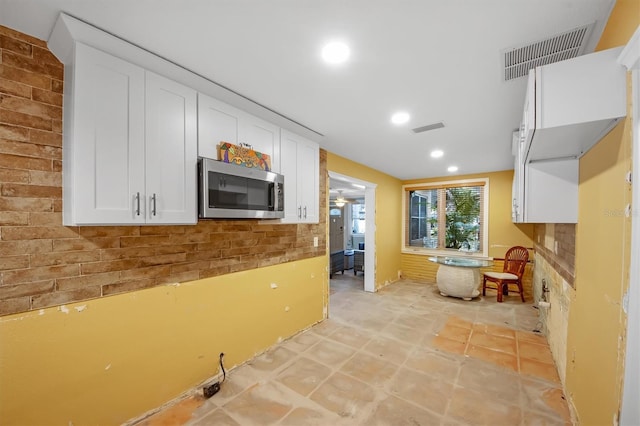 kitchen featuring white cabinets and brick wall