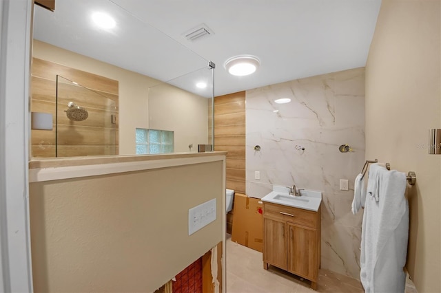 bathroom with vanity, a shower, tile walls, and toilet