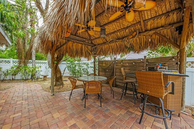 view of patio / terrace featuring a bar, ceiling fan, and a gazebo