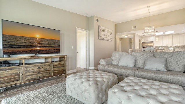 living area featuring wood finish floors, visible vents, and baseboards