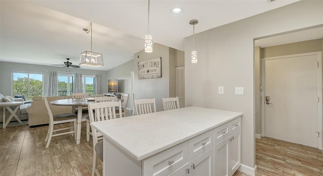 kitchen with open floor plan, hanging light fixtures, light wood finished floors, and white cabinetry