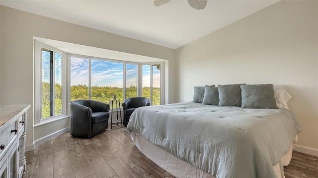 bedroom with lofted ceiling, multiple windows, and wood finished floors