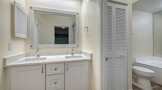 full bath with a closet, a sink, toilet, and double vanity