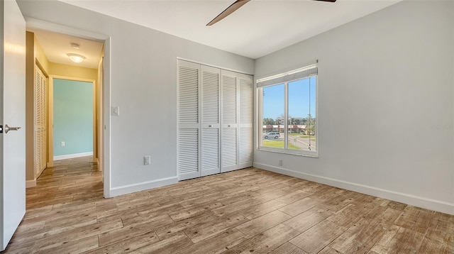 unfurnished bedroom with light wood-type flooring, baseboards, and a closet