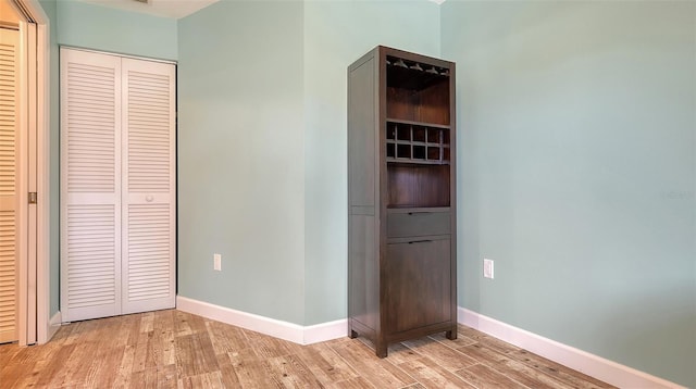 unfurnished bedroom featuring light wood-type flooring, baseboards, and a closet