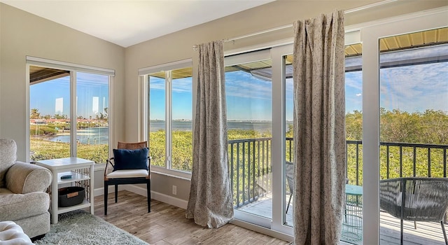 sunroom with lofted ceiling, a water view, and a healthy amount of sunlight