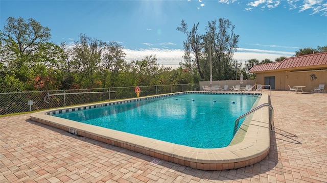 community pool with a patio and fence